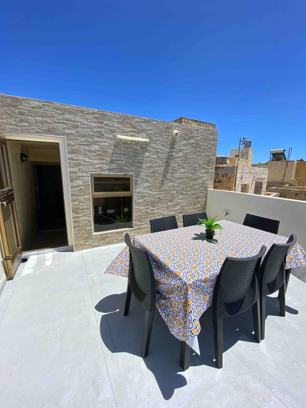 Sunlit roof terrace with outdoor dining and stone walls overlooking Senglea rooftops